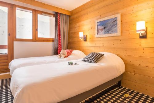 - 2 lits dans une chambre dotée de murs en bois et de fenêtres dans l'établissement Résidence Pierre & Vacances Aconit, aux Menuires