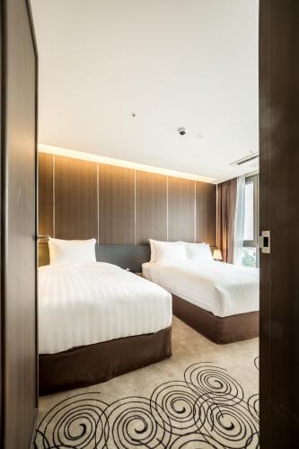 a hotel room with two beds and a window at Golden Daisy Hotel in Seogwipo