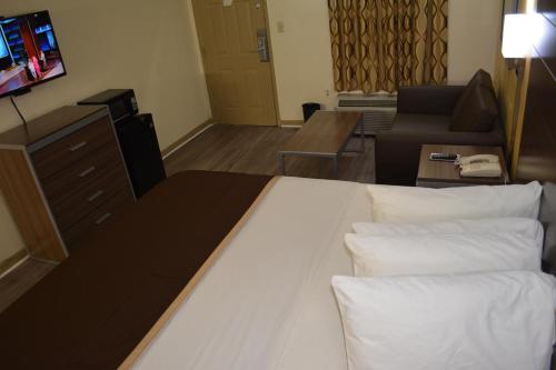 a hotel room with a bed and a living room at Southern Inn Lumberton in Lumberton
