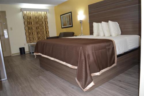 a hotel room with a large bed and a chair at Southern Inn Lumberton in Lumberton