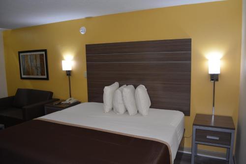 a hotel room with a bed with white pillows at Southern Inn Lumberton in Lumberton