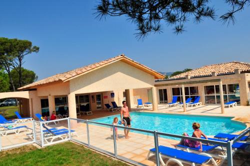una familia en la piscina de un complejo en Résidence Goélia Le Village Azur, en Puget-sur-Argens