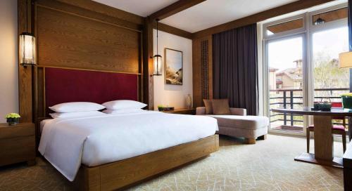 a bedroom with a large bed and a balcony at Hyatt Regency Changbaishan in Fusong