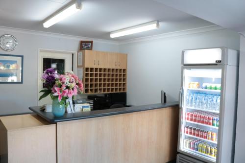 a kitchen with a refrigerator and a vase of flowers at Canning Bridge Auto Lodge in Perth