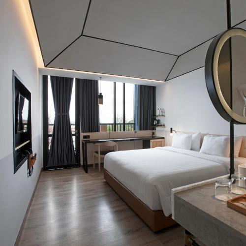 a hotel room with a bed and a table with a mirror at GAIA Cosmo Hotel in Yogyakarta