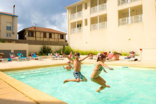 dos niños saltando en una piscina en Résidence Goélia Les Jardins de l'Oyat, en Mimizan-Plage