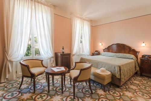 ガルニャーノにあるHotel Gardenia al Lagoのベッドルーム1室(ベッド1台、椅子2脚、テーブル付)