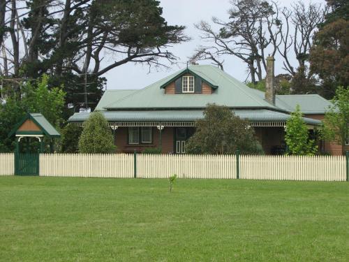 a house with a green roof and a fence at Butterfly Farm Bed and Breakfast Nirranda in Nirranda