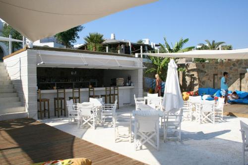 a patio with white tables and chairs and a bar at Gumbet Cove Hotel in Gümbet