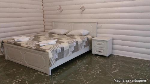 a bed with two pillows and a night stand in a room at Karpatska Forel in Svalyava