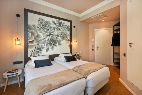 a bedroom with two beds and a painting on the wall at Hostal Central Barcelona in Barcelona
