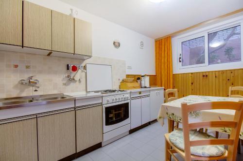 a kitchen with a stove and a sink and a table at Apartman Dragica in Mali Lošinj