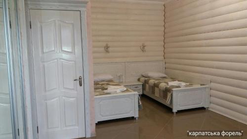 a small room with two beds and a door at Karpatska Forel in Svalyava