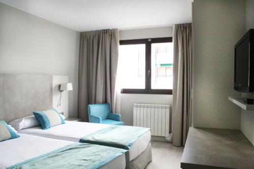 a hotel room with two beds and a blue chair at Hotel & Spa Real Jaca in Jaca