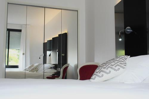 a bedroom with a white bed and a mirror at Hostellerie Du Grand Saint Antoine in Albi