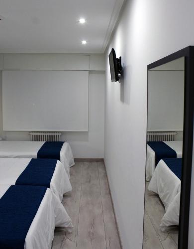 a hotel room with two beds and a mirror at Hotel Altiana in Ourense
