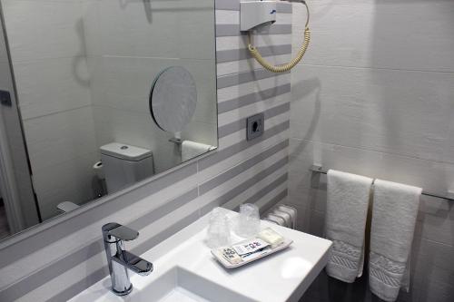 a white bathroom with a sink and a mirror at Hotel Altiana in Ourense