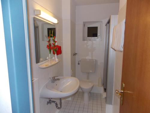 a white bathroom with a sink and a toilet at Hotel Krone in Bad Münster am Stein-Ebernburg