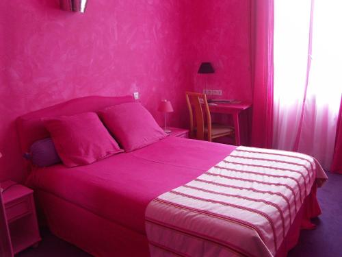 um quarto rosa com uma cama e uma mesa em Hôtel du Palais em Angoulême