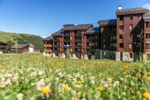 a field of flowers in front of a building at Residence Les Chalets des Arolles - maeva Home in Mâcot La Plagne