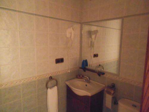 a bathroom with a sink and a mirror and a toilet at Hostal Los Galgos in Yepes