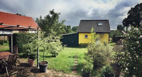 a backyard with a yellow house and trees at Gästehaus A+C Bovet in Wesenberg