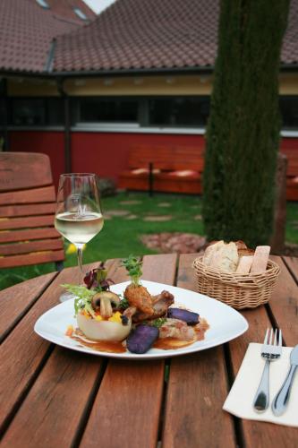 a plate of food and a glass of wine on a wooden table at Wein-Domizil Brennofen in Ilbesheim