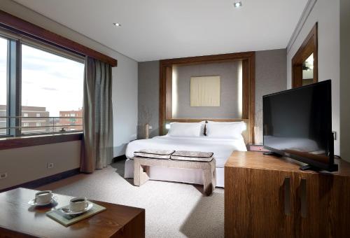 a hotel room with a large bed and a television at Eurostars Suites Mirasierra in Madrid