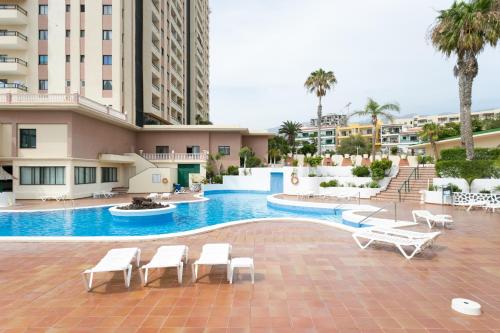 アデへにある906 lUXURY PARAíSO SEA VIEWの白い椅子とヤシの木があるホテルのプールを利用できます。