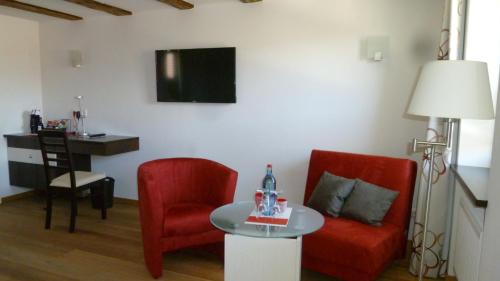 a living room with two red chairs and a table at Wein-Domizil Brennofen in Ilbesheim