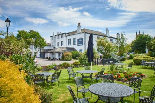 a garden with tables and chairs in front of a building at Trout Hotel in Cockermouth