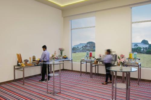 two people standing at a counter in a room with windows at Mercure Chennai Sriperumbudur in Sriperumbudur
