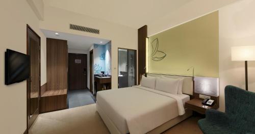 a hotel room with a bed and a chair at Mercure Chennai Sriperumbudur in Sriperumbudur