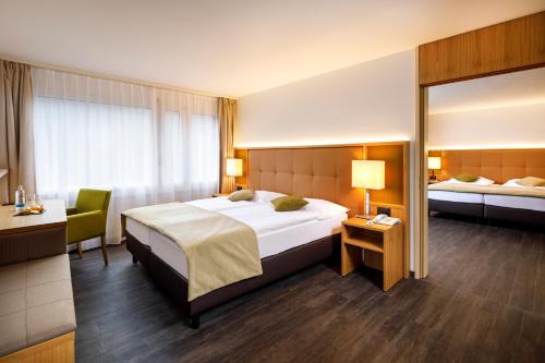 ein Hotelzimmer mit einem großen Bett und einem Schreibtisch in der Unterkunft Ramada by Wyndham Baden Hotel du Parc in Baden