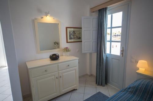 a bedroom with a dresser and a mirror and a window at Ianthe Apartments & Villa in Oia