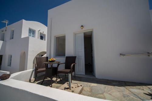 a patio with two chairs and a table in front of a building at Ianthe Apartments & Villa in Oia