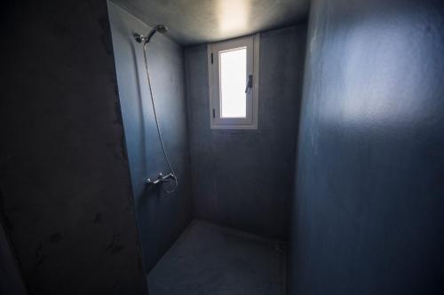 a bathroom with a shower stall and a window at Ianthe Apartments & Villa in Oia