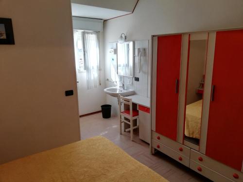 ein Bad mit einem roten Schrank und einem Waschbecken in einem Zimmer in der Unterkunft Hotel Devon Rooms & Breakfast in Cesenatico