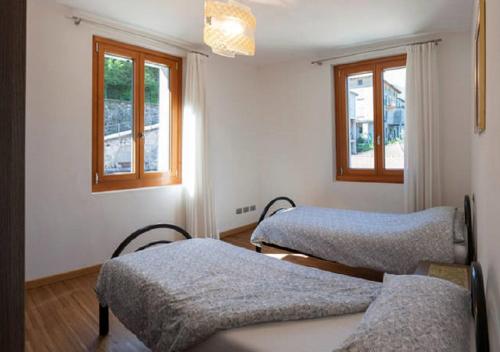 two beds in a room with two windows at Appartamento vista Lago - Mary in Lezzeno