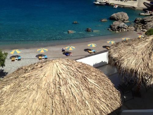 a view of a beach with umbrellas and the ocean at TO VOTSALO-beach side studios & taverna in Karpathos Town