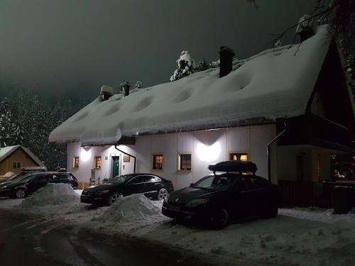 a snow covered house with cars parked in front of it at Apartmaji Koželj in Ribnica na Pohorju