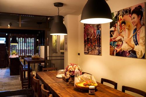 una sala da pranzo con tavolo in legno e fiori di Pak Ping The Cozy Living in Chiangmai a Chiang Mai