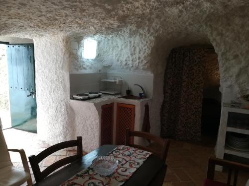 a dining room with a table and a kitchen at Cueva El Madrono in Pegalajar