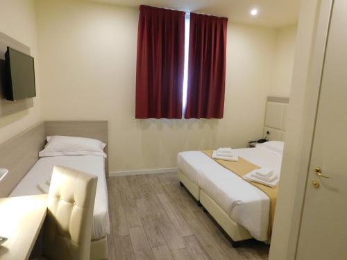 two beds in a room with a red curtain at Palace Hotel & SPA La CONCHIGLIA D' ORO in Vicenza