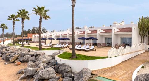 un complexe avec des chaises, des parasols et des palmiers dans l'établissement L' Amphitrite Palace Resort & Spa, à Skhirat