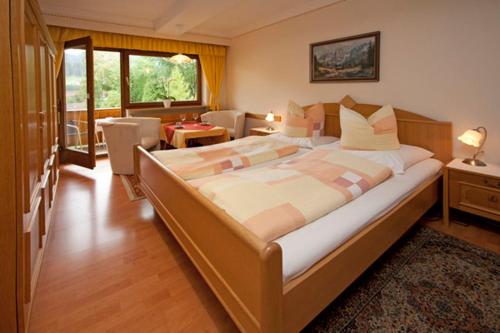 a bedroom with a large bed and a living room at Gästehaus-Pension Bendler in Kirchdorf in Tirol