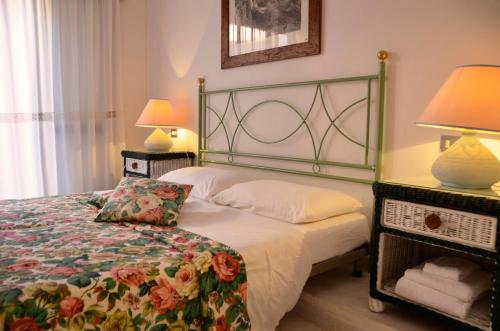 a bedroom with a bed with a floral bedspread and two lamps at Villa Flamingo in Villasimius