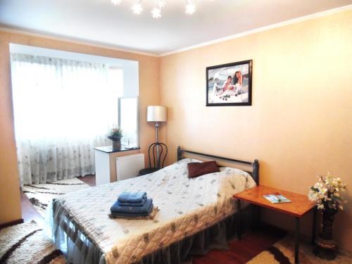 a bedroom with a bed and a table and a window at заречанская 57/1 in Khmelʼnytsʼkyy