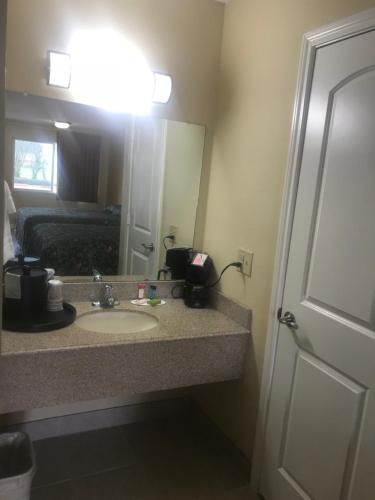 a bathroom with a sink and a mirror and a bed at Navasota Inn in Navasota