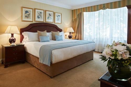 a bedroom with a large bed and a vase of flowers at Cheval Thorney Court at Hyde Park in London